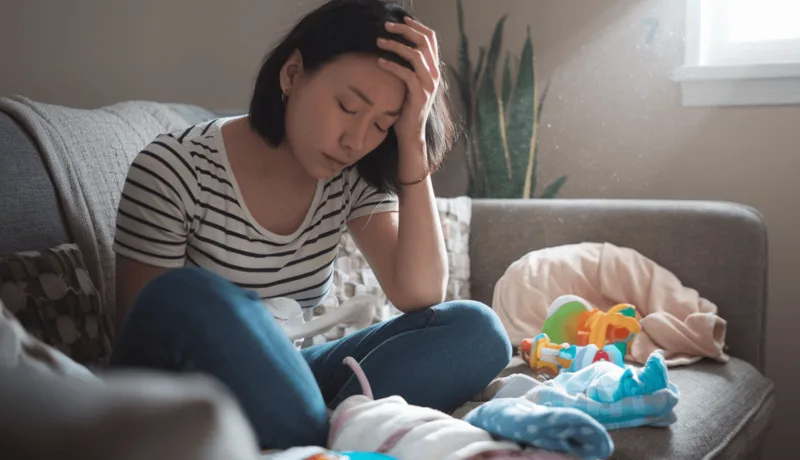 육아 번아웃 증후군 극복하기: 지친 부모를 위한 7가지 자기돌봄 방법 a woman sitting on a couch with baby clothes