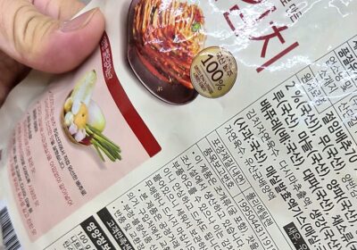 마트 포장김치 뒷면 원산지 표시 직접 확인 - Useful Life Hub 마트에서 동원F&B 양반 썰은김치 봉지를 손으로 뒤집어 뒷면 원재료명과 원산지 표시란을 확인하는 모습