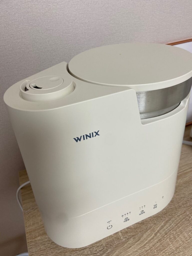 분무 노즐과 스테인리스 물통 - Useful Life Hub 위에서 본 가습기 분무 노즐과 둥근 물통 뚜껑 — 초음파 가습기 세척 부품